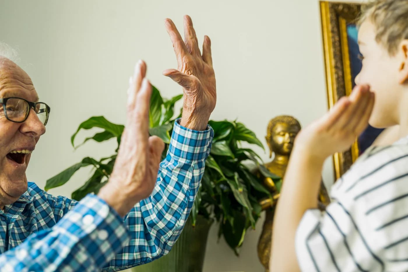A grandfather’s hand high-fives a five-year-old, in a close crop.