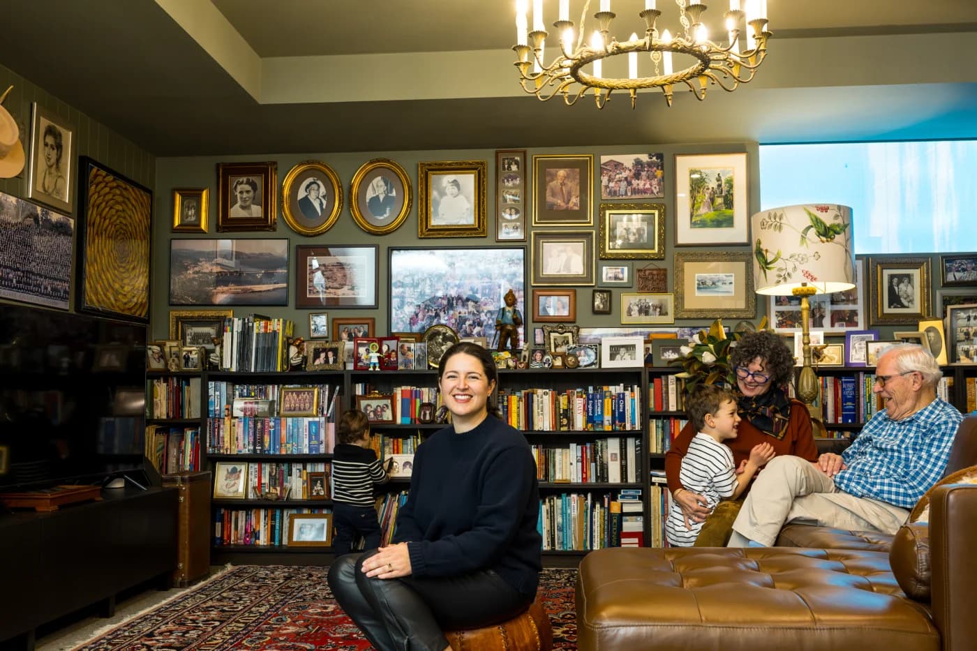 A family sits in a library with salon-hung portraits around them.